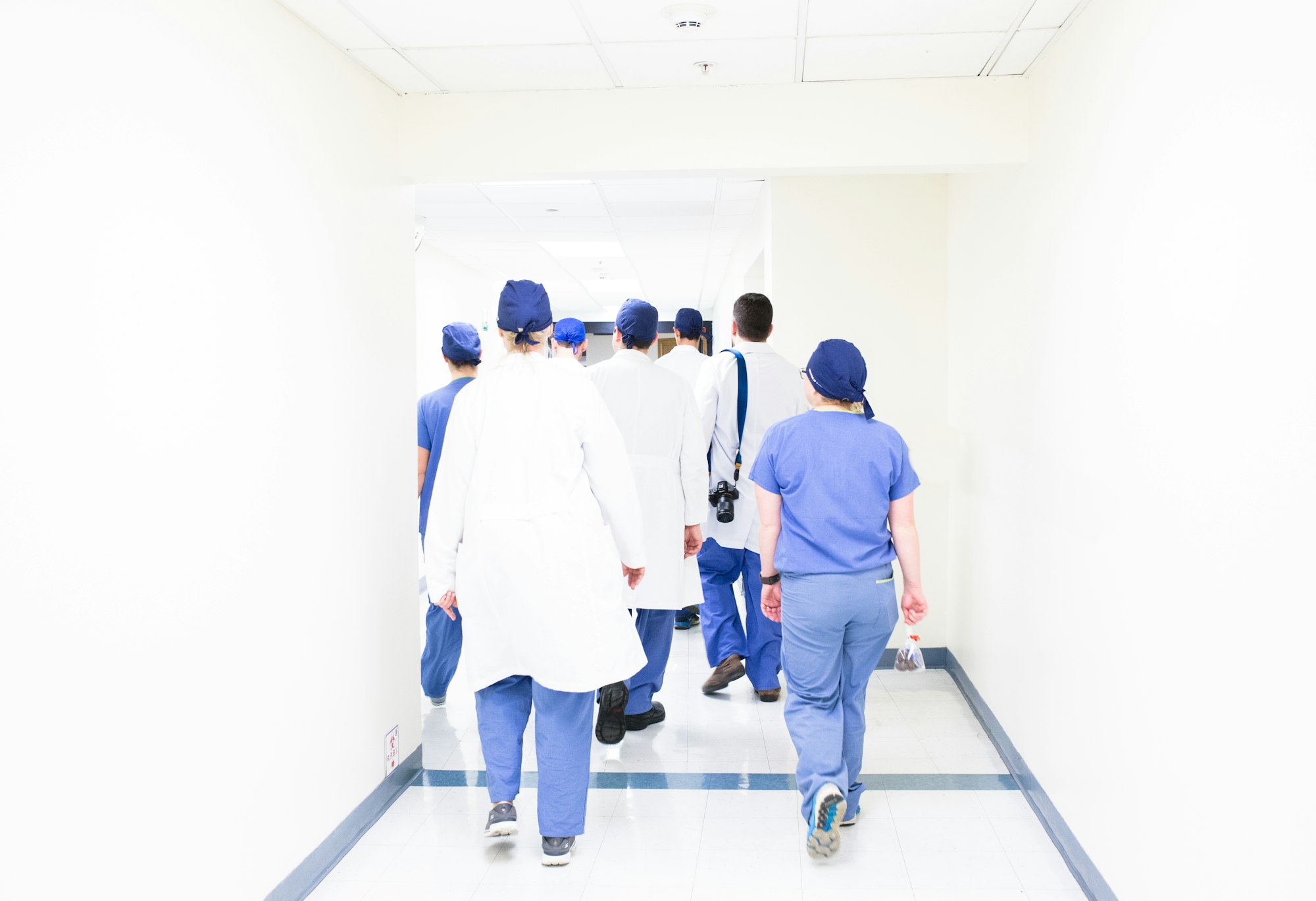 Hospital staff in scrubs walking down a bright corridor