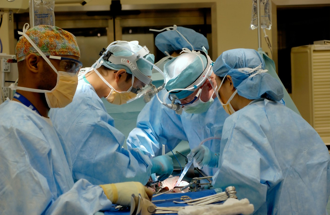 Four surgeons in blue gowns during an operation